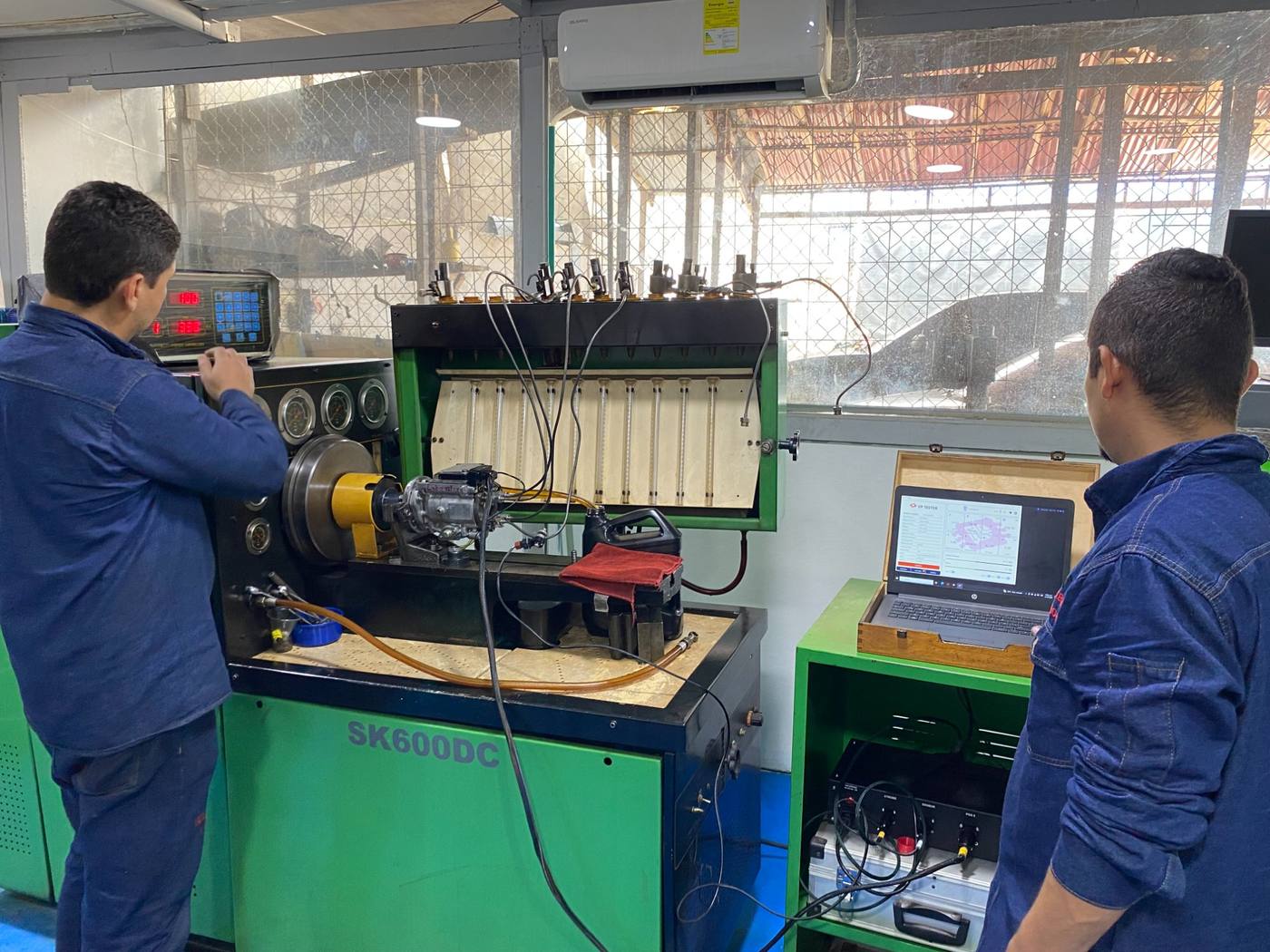 Técnico operando banco de pruebas SK600DC con laptop de diagnóstico